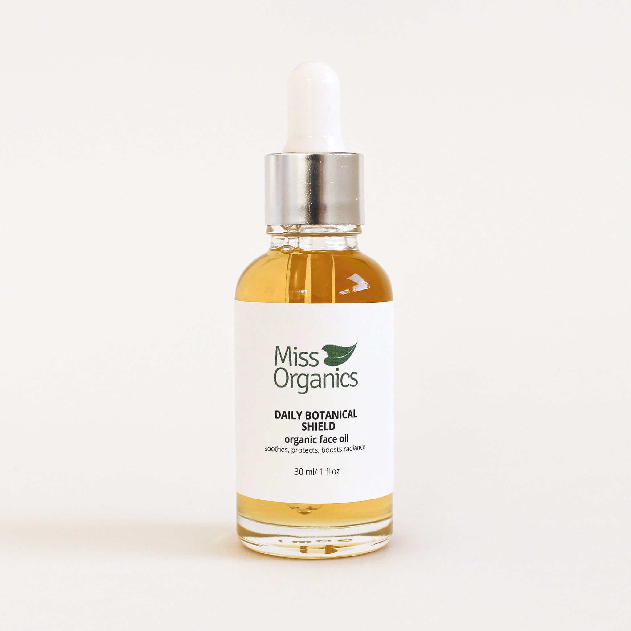 Daily Botanical Shield Organic Face Oil in glass bottle on cream background