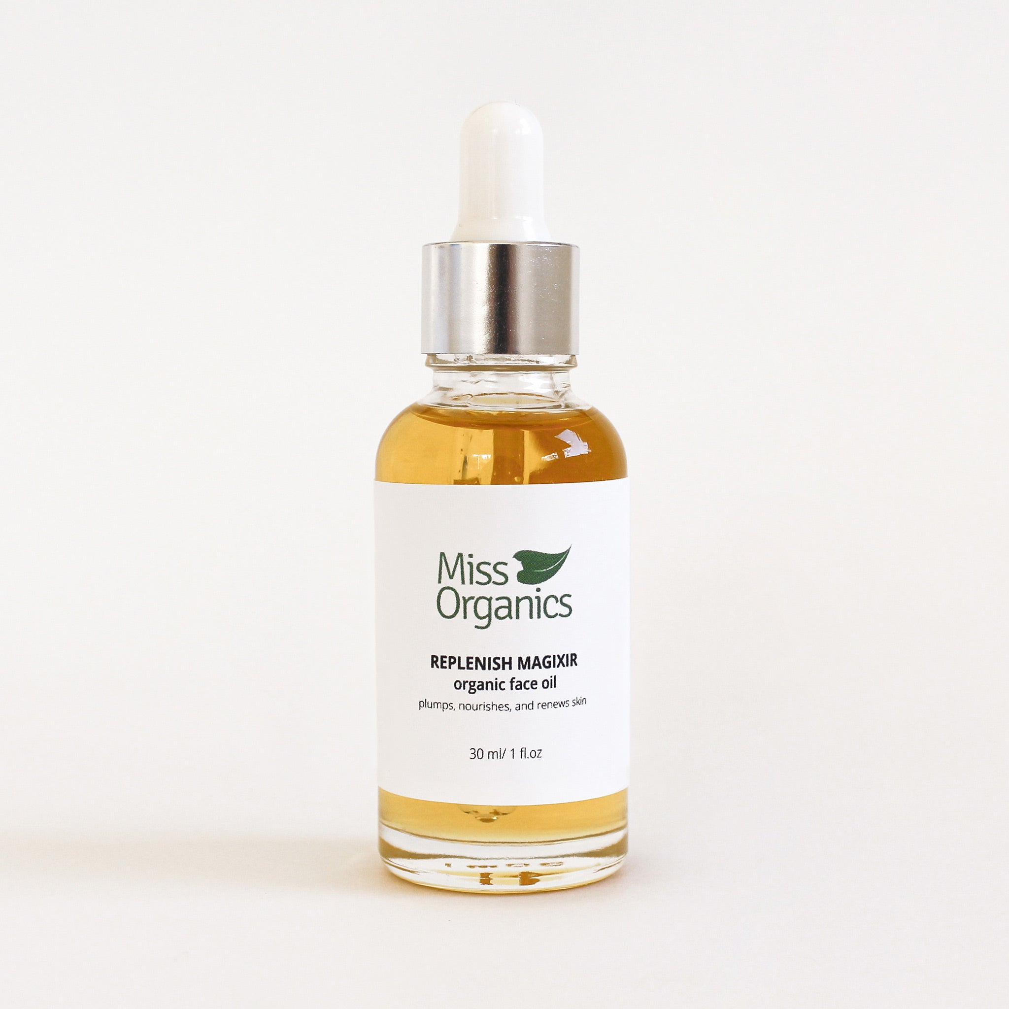 Replenish Magixir Organic Face Oil in glass bottle on plain  cream background
