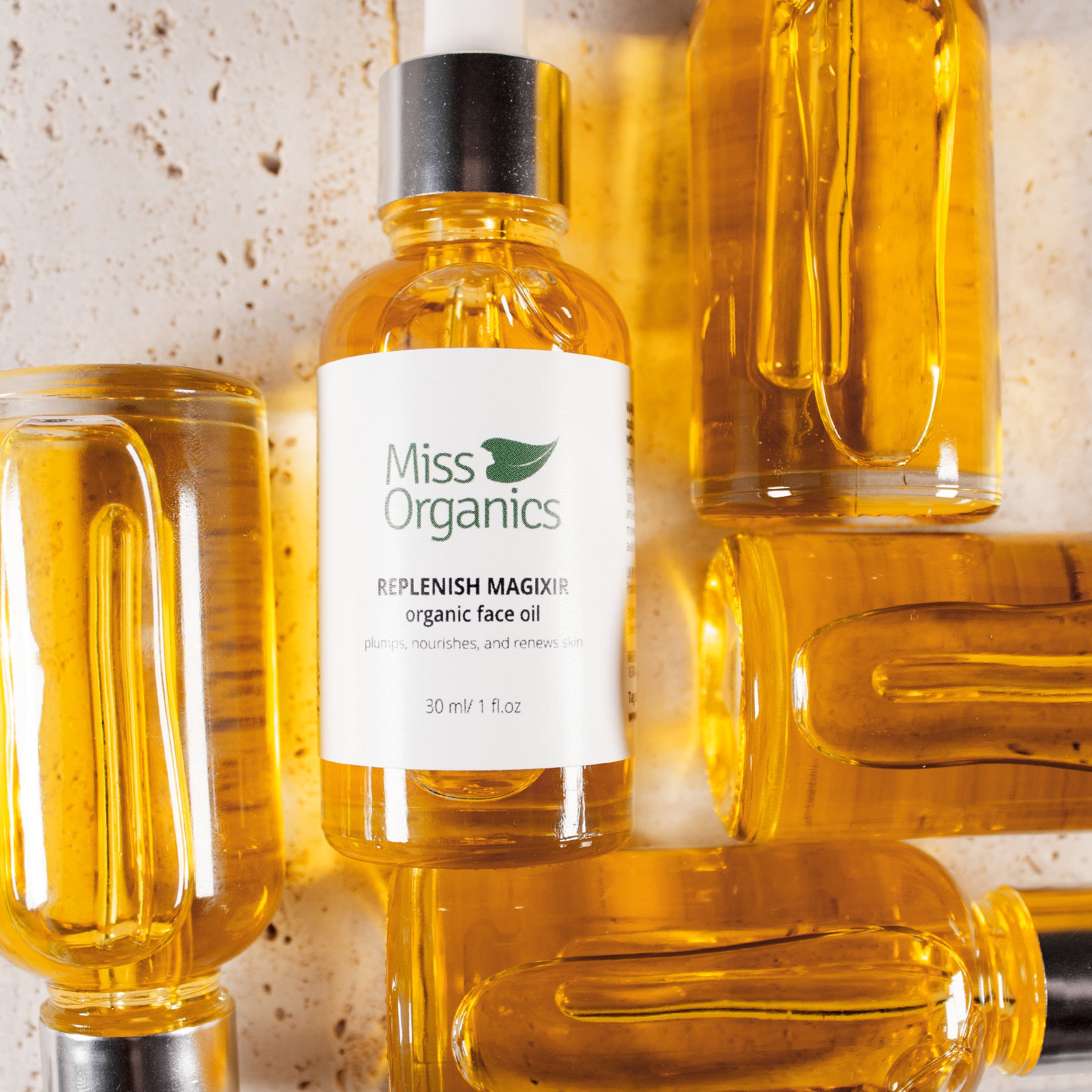 Replenish Magixir Organic Face Oil in glass bottle on stone background by Miss Organics